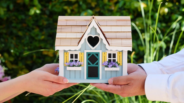 two people holding a small model of a home